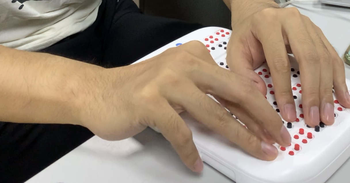 图为视障学生试用盲用分数辅助运算器样机