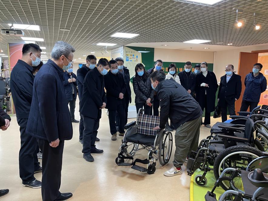 图为向来访人员介绍轮椅